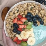 a person holding a bowl of fruit and cereal